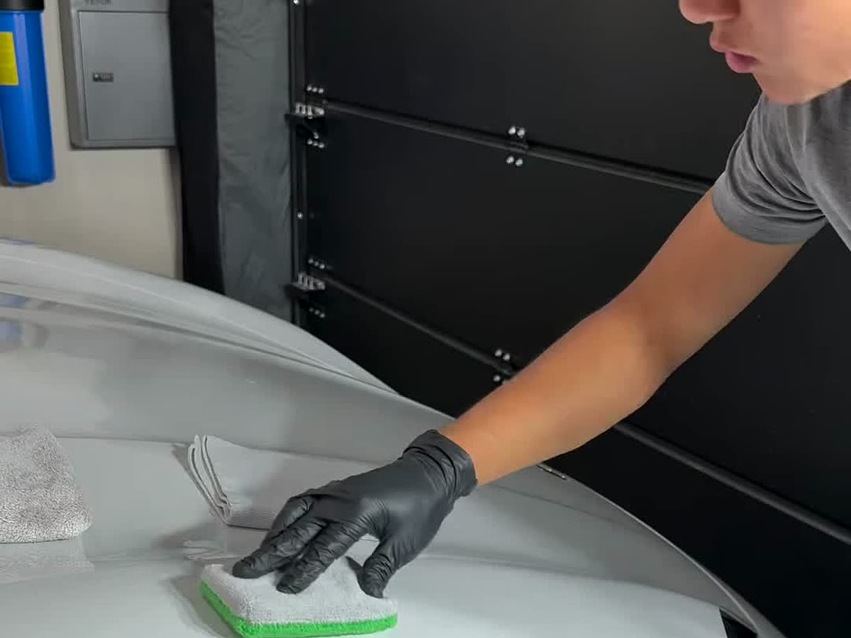 Applying ceramic coating by hand to the front fender of a white Porsche 911
