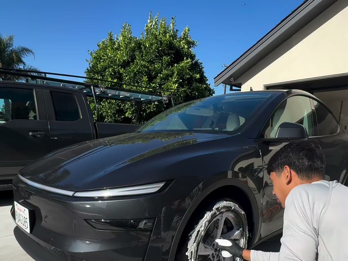 Obsidian Detail Lab hand-cleaning the front wheel of a black Lucid Air