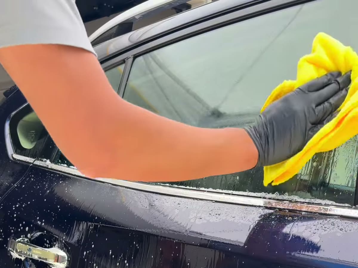 Wiping down a freshly washed window with a microfiber towel
